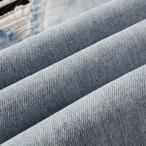 Close-up of light blue denim fabric texture with distressed details and twill weave