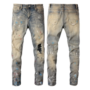 Slim fit distressed jeans for men featuring graffiti paint splatters and ripped details