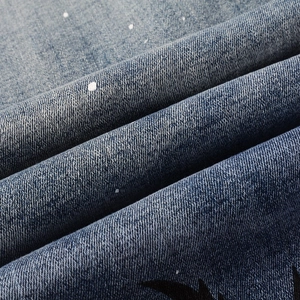 Close-up of blue washed denim fabric with white paint splatter and street style graphics