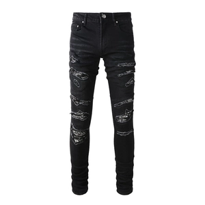 Men's slim fit black ripped jeans featuring distressed paisley patches and a tapered cut