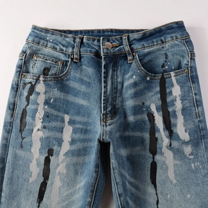 Dettaglio dei jeans slim fit blu con schizzi di vernice graffiti e motivi a macchia d'inchiostro