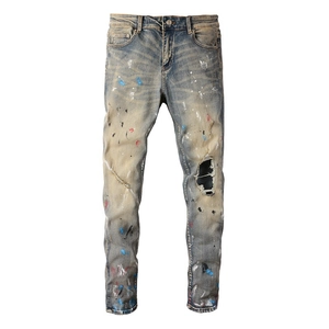 Macro shot of distressed light blue denim with colorful paint splatters and ripped knee detail