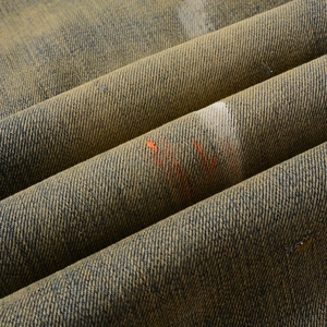 Makro-Detail von Denim-Stoff mit Mud-Wash-Finish und orangefarbenen Farbspritzern