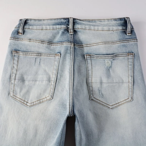Détail arrière du jean bleu clair avec poches effilochées et effet de délavage vintage