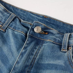 Vue macro du bouton métallique et coutures orange sur un jean denim bleu vintage