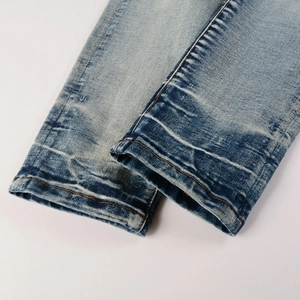 Close-up of light blue washed denim hem with orange double stitching and twill texture