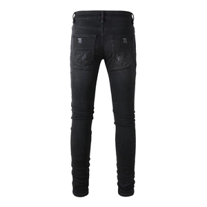 Detail shot of distressed back pocket on men's slim fit black ripped denim jeans