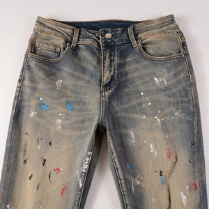 Detail of distressed denim with multi-color paint splatters and vintage wash texture