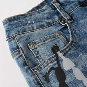 Dettaglio dei jeans azzurri con schizzi di vernice bianca e stampa di silhouette nera