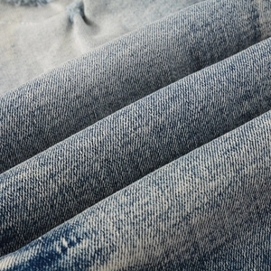 Macro detail of washed light blue denim fabric with twill texture and distressed edge