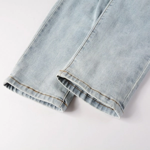 Detailed close-up of light blue denim hem with precision yellow double stitching