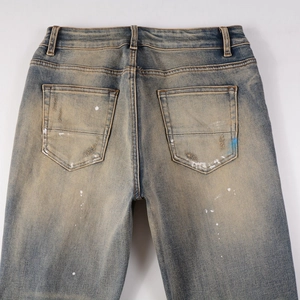 Detailed view of vintage washed denim with white paint splatters and distressed back pockets
