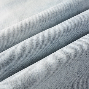 Close-up of light blue washed denim fabric with premium twill texture and soft fade