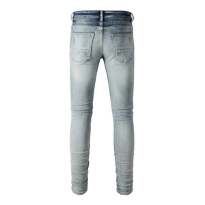 Detail of light blue distressed denim jeans showing back pockets and washed texture