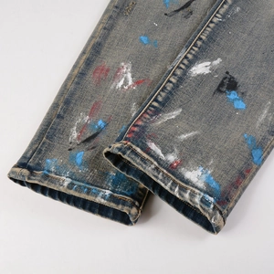 Close-up of multicolored paint splatter and distressed hem detail on denim jeans