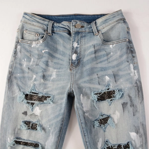 Slim fit light blue distressed jeans with star-shaped holes and black rhinestones decoration