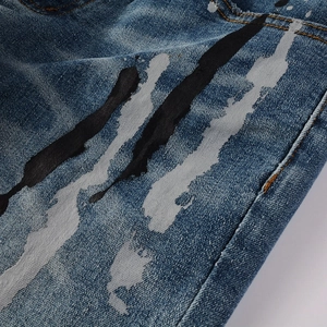 Dettaglio del tessuto denim blu scuro con schizzi di vernice bianca e nera artistica