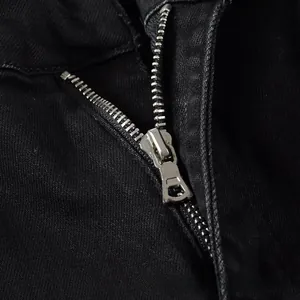 Detailed macro view of the silver metal zipper and twill fabric on black slim denim jeans