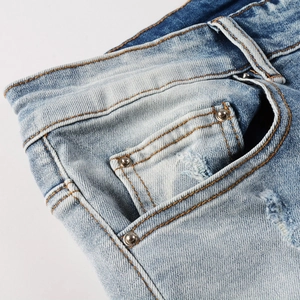 Gros plan détaillé du denim bleu vieilli avec rivets en cuivre et coutures orange classiques