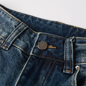 Detailed close-up of dark blue jeans waist with metal button and orange contrast stitching