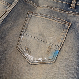 Close-up of distressed back pocket on men's vintage jeans with white paint splatter