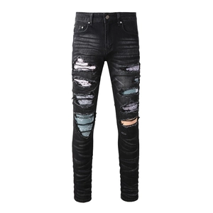 Detail of slim fit black jeans featuring colorful paisley patches and distressed rip details