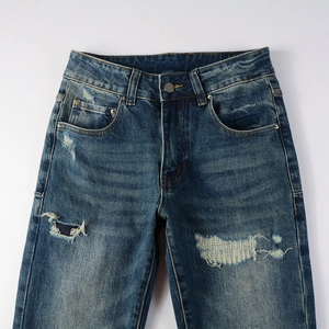 Detailed view of dark blue distressed jeans with whiskers and reinforced patch details