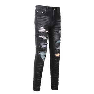 Detailed close-up of distressed denim jeans featuring colorful patterned fabric patches