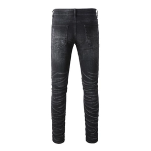 Detail view of black distressed jeans featuring tiger-stripe fading and ripped back pockets