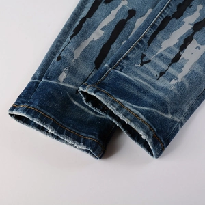 Dettaglio dell'orlo usurato su jeans blu con strisce verticali di vernice spray art