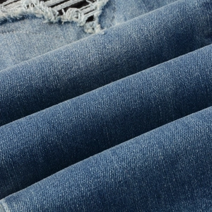 Détail rapproché du tissu denim bleu vintage avec trous usés et texture en sergé
