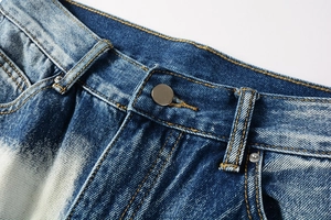 Detailed close-up of retro washed blue denim jeans waist with yellow stitching and metal button
