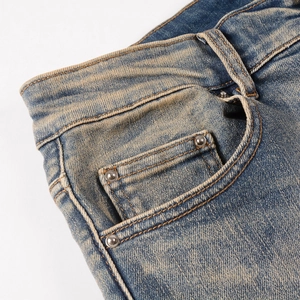 Close-up of vintage blue denim jeans featuring heavy wash texture and metal rivets