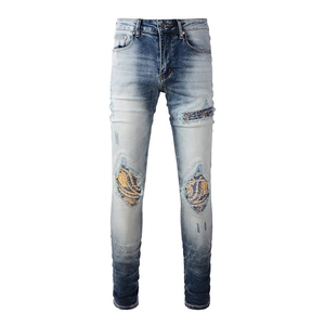 Detailed macro view of distressed denim jeans with blue and yellow wave pattern patches