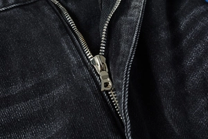 Détail du tissu denim gris foncé délavé avec une fermeture éclair métallique robuste