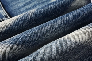 Macro texture of washed indigo denim fabric with twill weave and vintage faded details