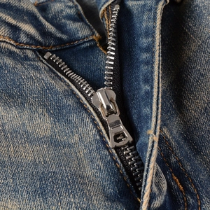 Close-up of durable metal zipper and stitching on retro washed blue denim jeans