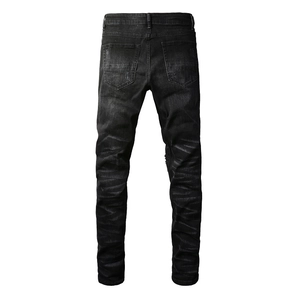 Detail view of the back of slim-fit black denim jeans with washed texture and cat-whisker fades
