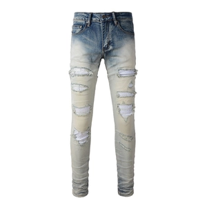 Dettaglio dei jeans slim fit blu chiaro con effetto invecchiato e toppe di strass lucidi