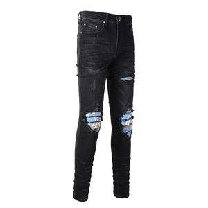Detail view of men's slim fit black ripped jeans with stylish blue plaid fabric patches
