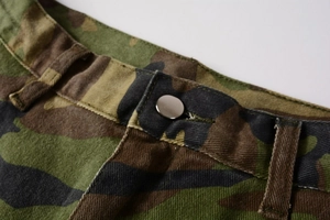 Detailed macro view of jungle camouflage cargo pants waist with metal button and belt loops