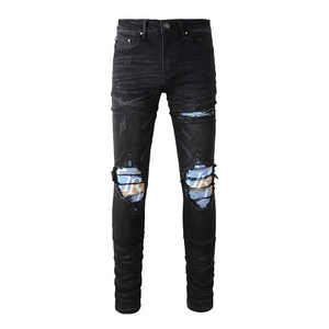 Detail of knee rips with blue textured lining on black slim fit men street jeans