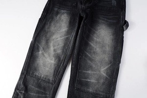 Détail de la texture denim noir délavé et des renforts aux genoux du jean cargo homme