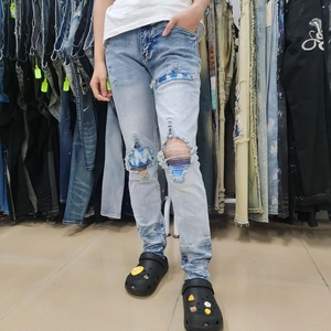 Detail of light blue washed jeans featuring ripped knee design with striped lining fabric