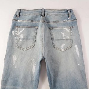 Detail view of back pockets with white paint splatter and cat whisker fading on blue jeans