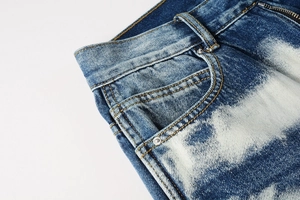 Macro shot of dark blue denim jeans showing yellow stitching and metal rivet detail