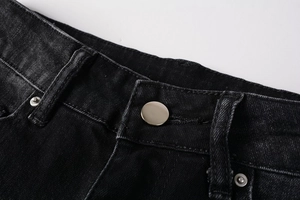 Macro shot of black denim jeans waist with silver button and reinforced stitching details