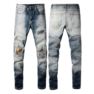 Detailed close-up of blue distressed jeans with vintage patches and ripped knee texture