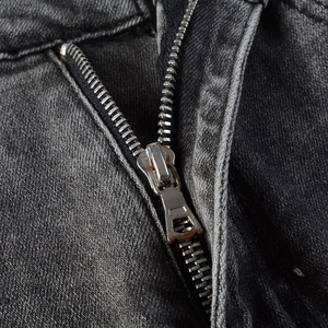 Close-up of a silver metal zipper on vintage dark grey slim fit stretch denim jeans