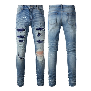 Detail view of men's distressed jeans with blue sequin patches and white paint splatters